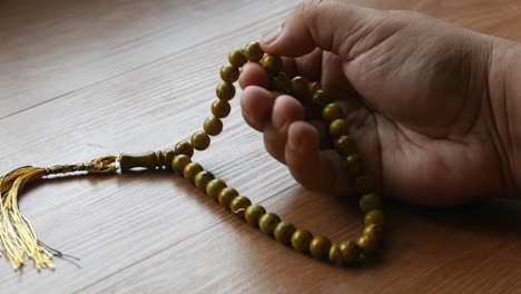hombre musulmán orando con cuentas de rosario en la mano