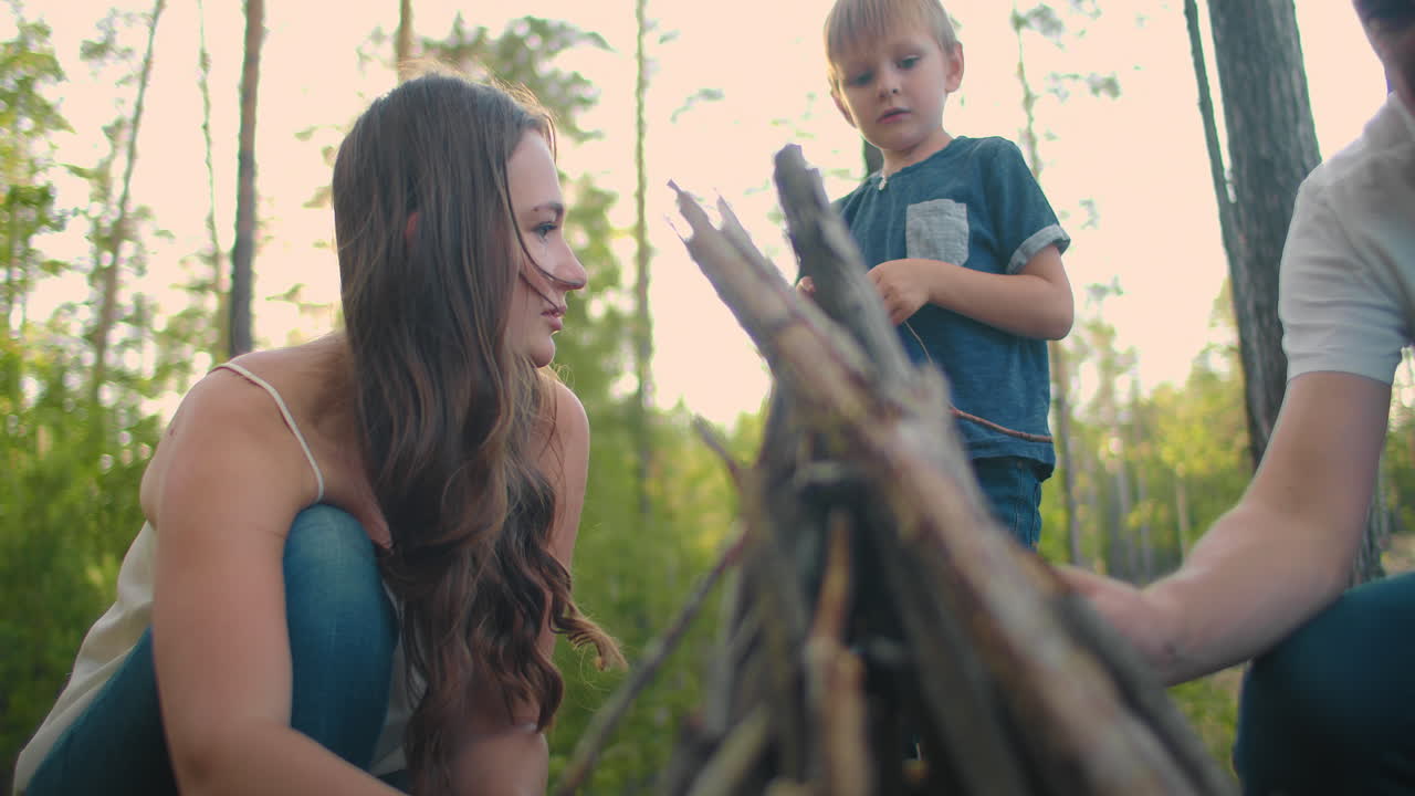 familias en la naturaleza juntas recogen e instalan un fuego para cocinar. viaje familiar al bosque. caminata con una tienda y una estancia nocturna en el bosque junto al fuego