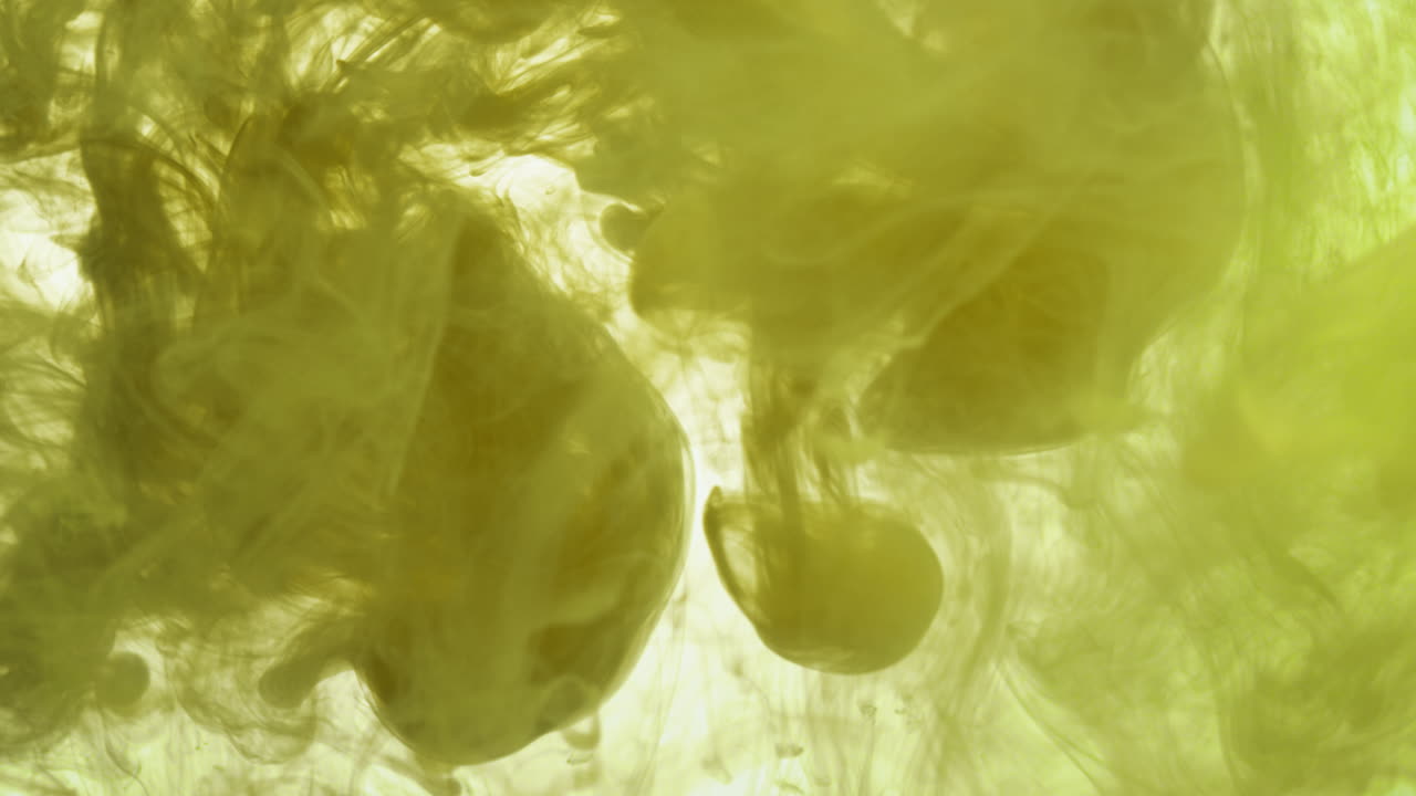 желтая краска или краситель, сброшенные в воду на белом фоне для создания вихревого цветного дымового фона 4