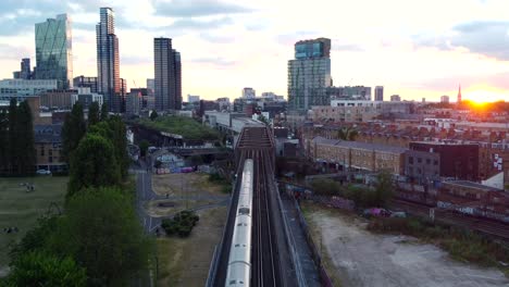 static drone shot train travelling on railway through city in britain