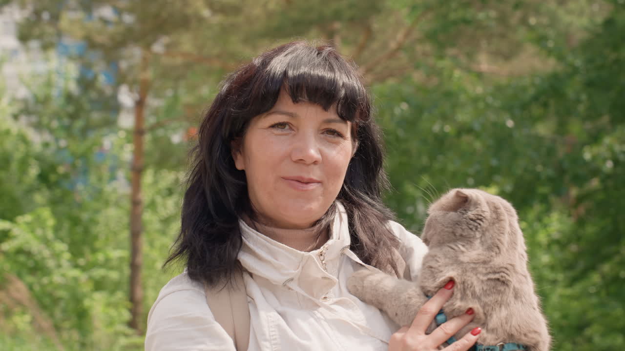 White Woman Outdoors Holding Cat Among Pine Trees, Affectionate Closeup With Gentle Smile, Light Jacket And Scarf, Soft Sunlight, Nature Walk Vibe, Hobbyist Rescuer Caring For Pet, Calm Countryside