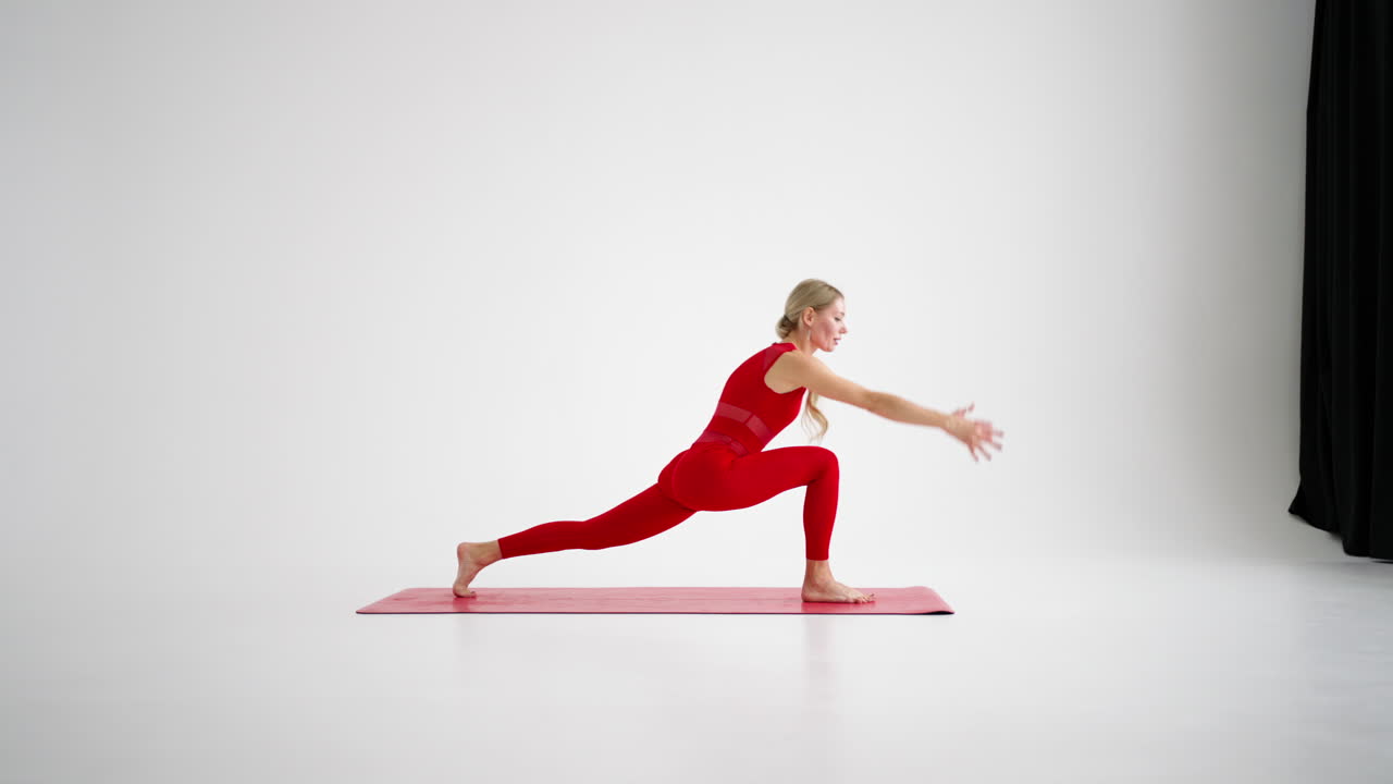 Millennial woman stretching in yoga pose meditation isolated on white background in red Sportswear. Portrait of young female yoga practitioner posing for copy space. 4k