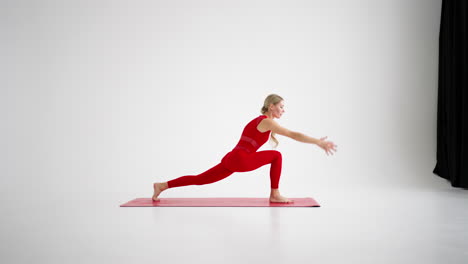 Millennial-woman-stretching-in-yoga-pose-meditation-isolated-on-white-background-in-red-Sportswear.-Portrait-of-young-female-yoga-practitioner-posing-for-copy-space.-4k