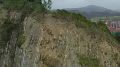 aerial descends to reveal rocky cliff edges at itzurun beach, extreme closeup