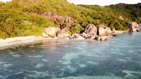 aerial open shot of the famous beach on seychelles, la digue island with view on lagoon and seychelles stones and green hills