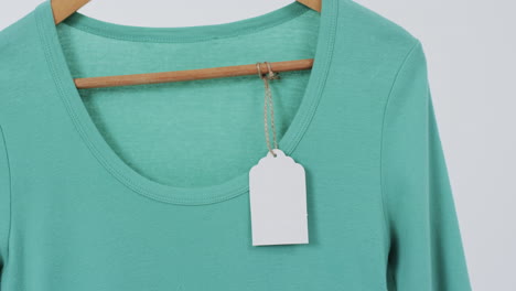 video van groen t-shirt met tag op hanger en kopieerruimte op witte achtergrond