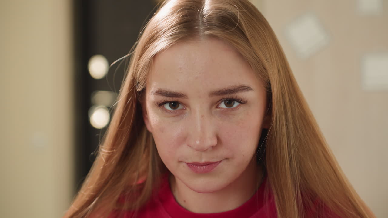 따뜻한 음료를 마시며 실내에서 평온함을 즐기는 젊은 여성, 뜨거운 차를 홀짝이며 차분하게 앉아 있는 편안한 금발의 여성, 조용한 티타임에 몰두하는 여성의 모습이 돋보이는 조용한 실내 풍경