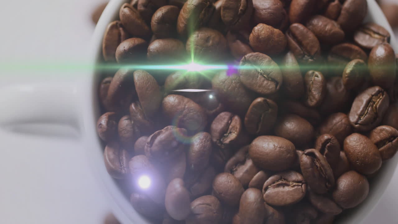 Macro shot showing dark roasted coffee beans catching lens flare reflections inside ceramic mug