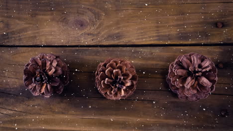 nieve cayendo con la decoración de cono de pino de navidad en madera