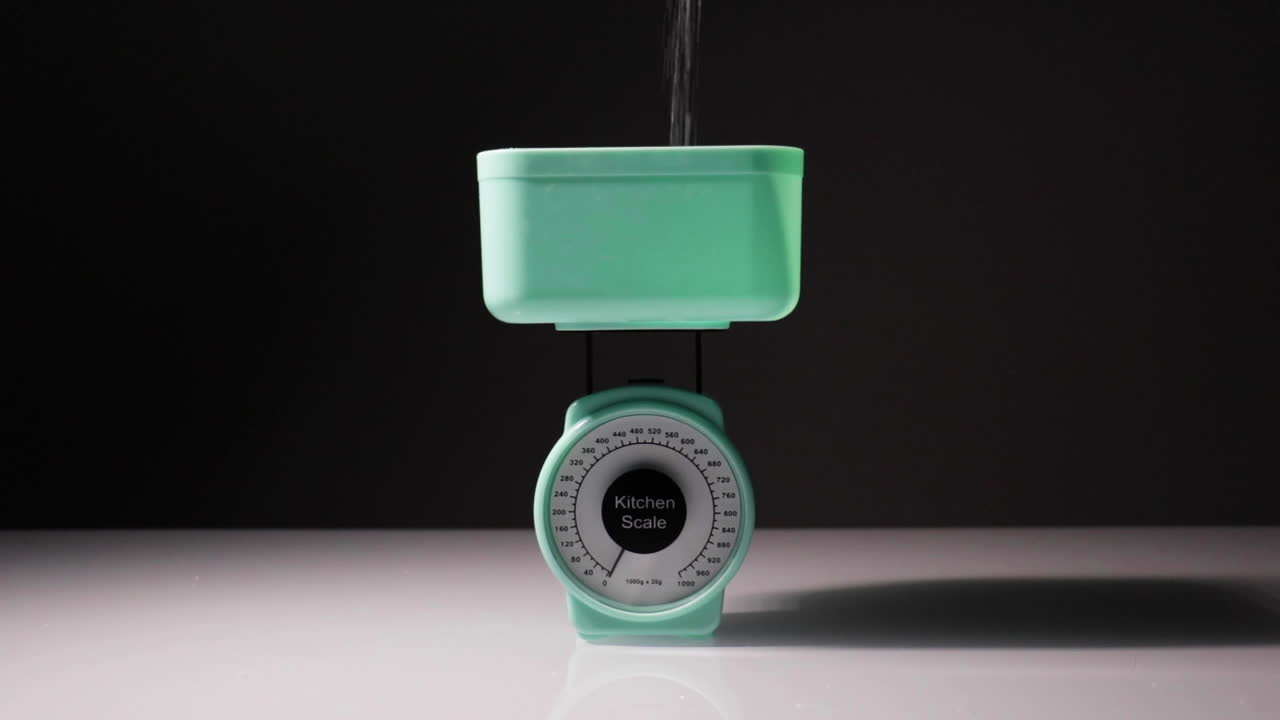 tiro a cámara lenta de azúcar que se vierte en un conjunto de escalas que pesan 120 gramos