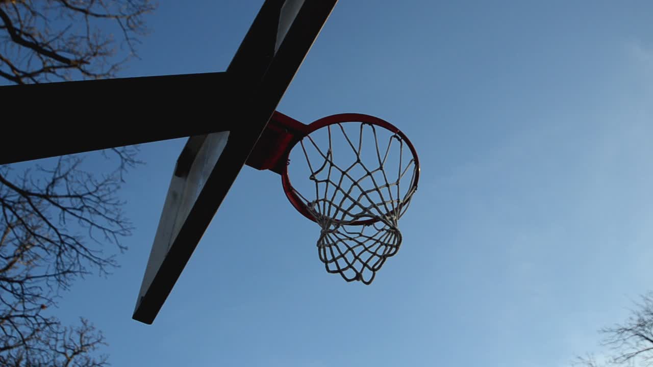una vista desde debajo de un gol de baloncesto con un cielo azul como fondo