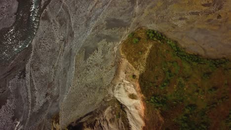 aerial view above a river flowing and natural textures and patterns of the icelandic terrain