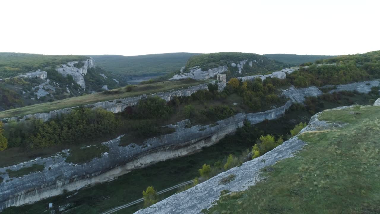 vista aérea de un valle de montaña con acantilados y ruinas