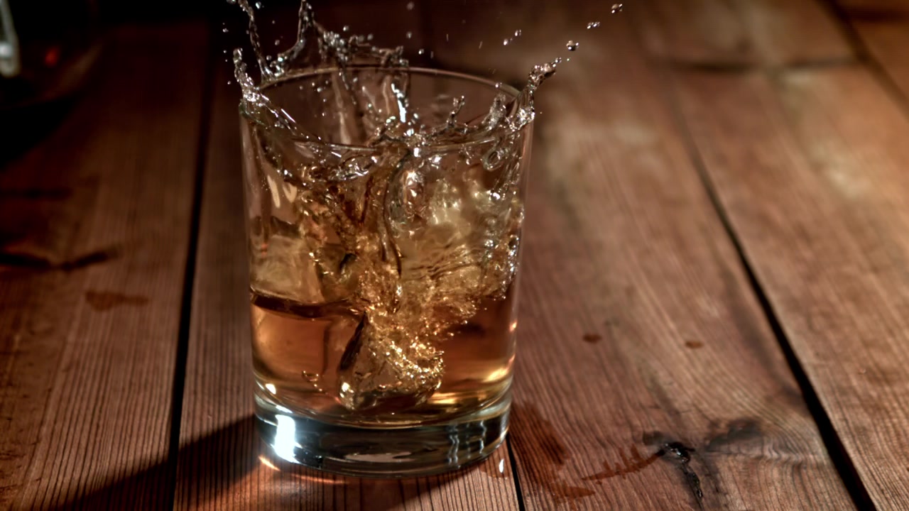 Caduta di cubetti di ghiaccio in un bicchiere di whisky al rallentatore