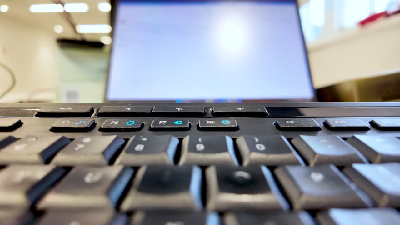 Close Up of Black Computer Keyboard with Laptop Screen in Background for Typing Programming and Technology Concepts in Office Environment