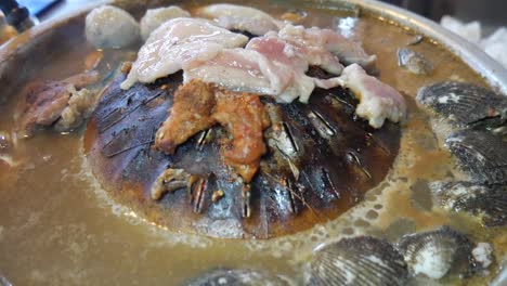 thailand style hotpot with centre grill cooking pork and clam