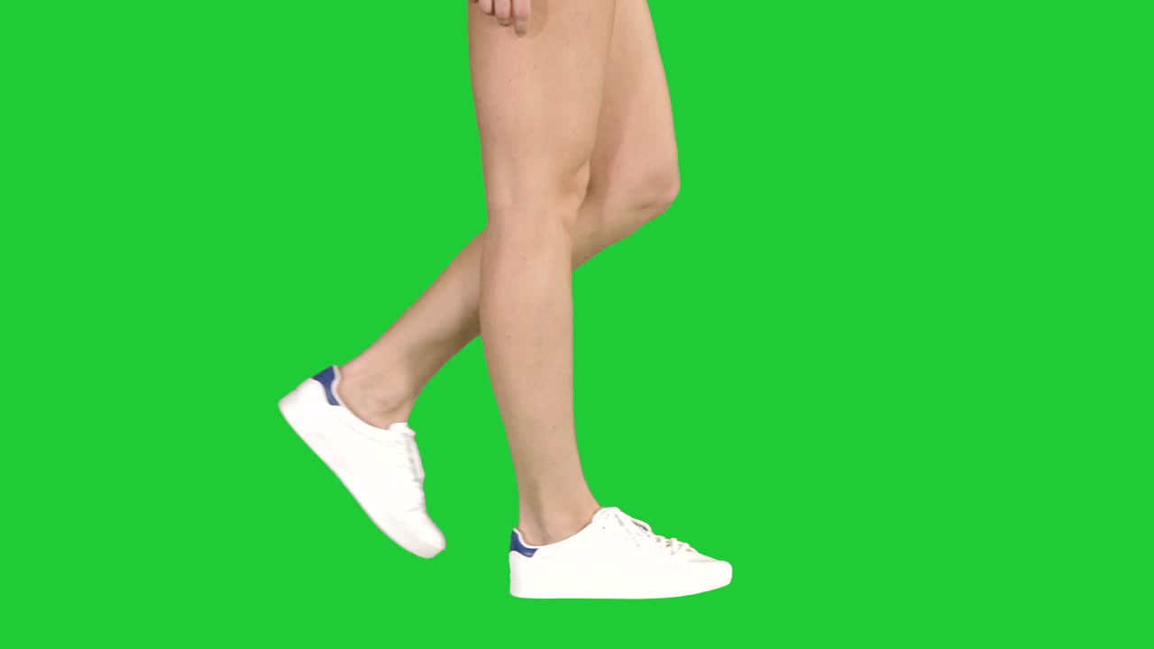 Women feet wearing white sneaker shoes walking on a Green Screen, Chroma Key