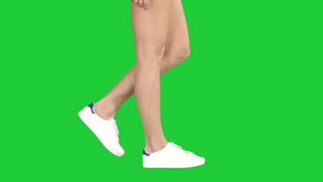 women feet wearing white sneaker shoes walking on a green screen, chroma key