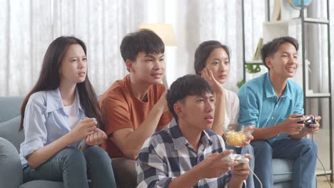 asian teenagers friends playing video games at home and disappointed