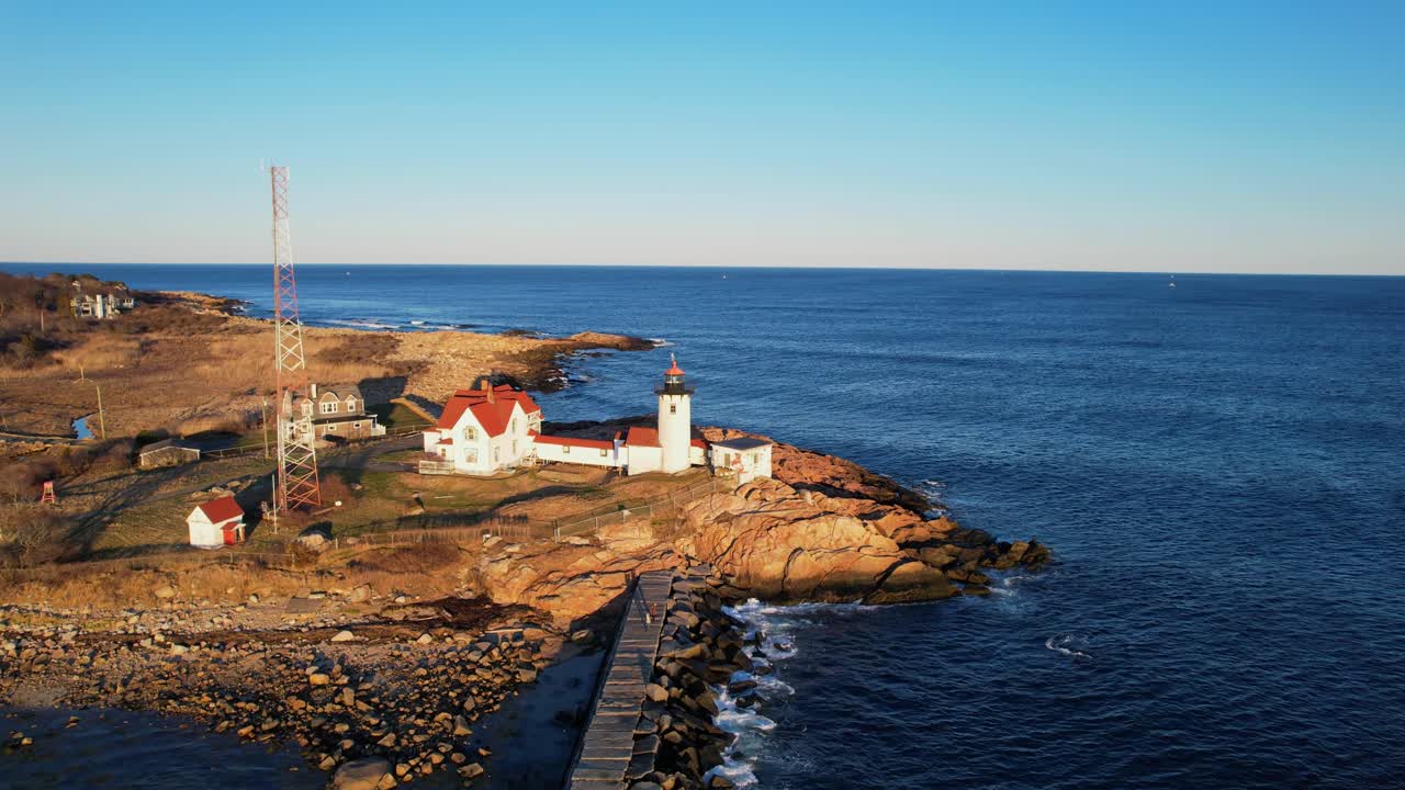 Drönarflygning framåt längs Dog Bar-vågbrytaren mot Eastern Point fyr vid den klippiga Eastern Point-utkiksplatsen, Gloucester, Massachusetts, USA.