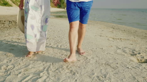 a young couple is walking barefoot on the sand on the beach in the frame only the legs are visible v