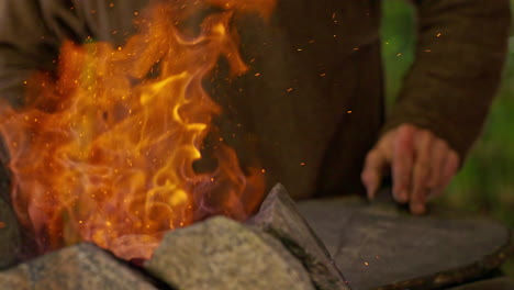 blacksmith uses bellows to heat a fire before making a blade in a forge