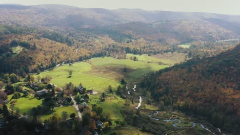 Aerial-forwarding-shot-of-rural-landscape-with-the-view-of-a-village-by-the-side-of-hills-covered-with-forest-on-a-cloudy-day-in-Litchfield-county,-Connecticut,USA