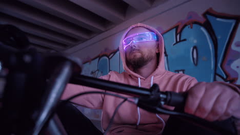 an urban biker sporting futuristic glasses stands confidently under colorful graffiti art