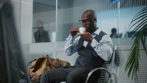 man drinking coffee in airport lounge