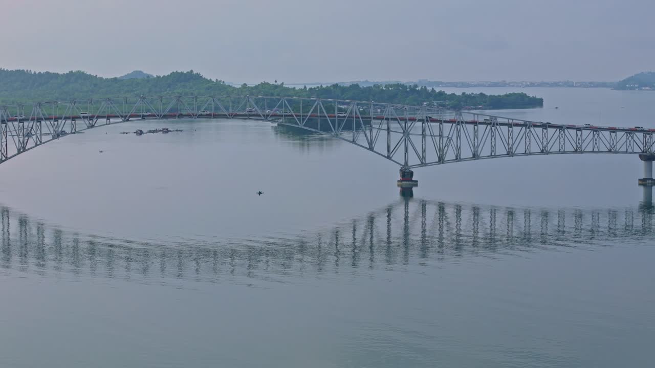 Pan shot of San Juanico Bridge above wide waters, misty mountains frame the scene