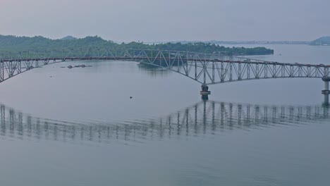 pan shot of san juanico bridge above wide waters, misty mountains frame the scene