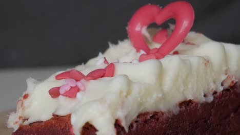 close-up of a red velvet brownie with white frosting and heart-shaped decoration