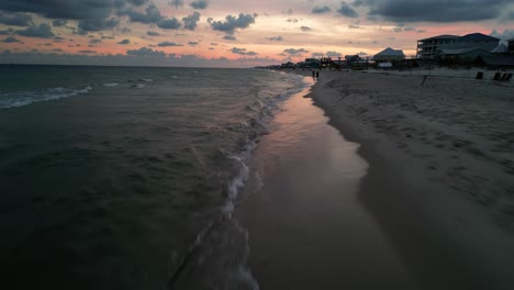 disparo de drone bajo moviéndose hacia la puesta de sol en la costa de alabama en la playa