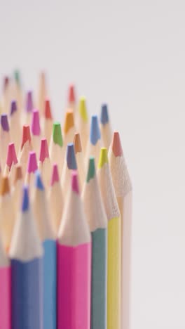 vertical video studio shot of rotating multi-coloured pencils against white background 2