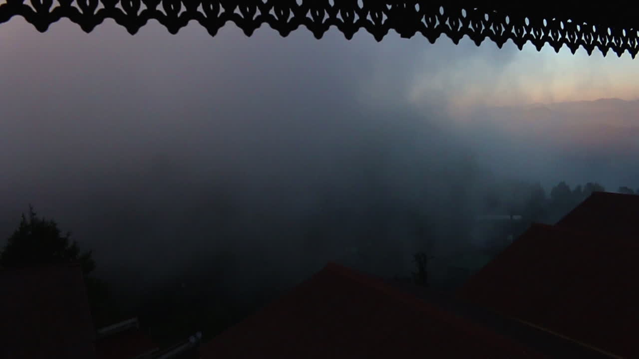 View of dense fog movement from a balcony window during the early morning hours in Mussoorie, India, pan sliding slow motion shot.