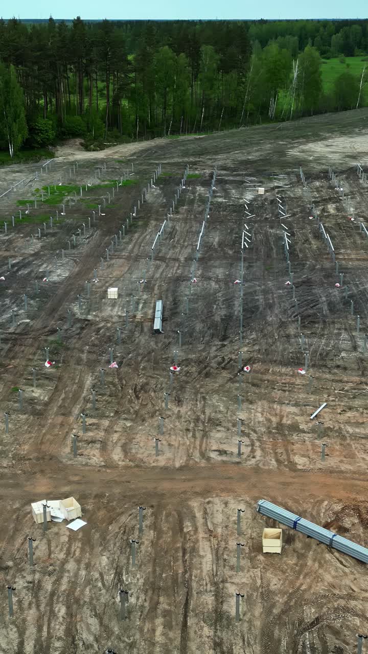 Solar farm construction site in Latvia with land clearing and mounting posts for solar panels installation - Aerial drone vertical shot