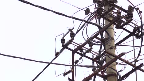 slow motion pan of a transformer with tangled wires isolated against a cloudy sky