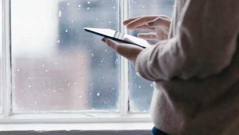 close-up-woman-hands-using-digital-tablet-computer-browsing-online-messages-reading-social-media-enjoying-mobile-touchscreen-device-standing-by-window-relaxing-at-home-on-cold-rainy-day