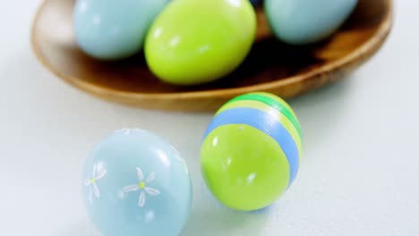 colorful easter eggs in bowl with two painted easter eggs