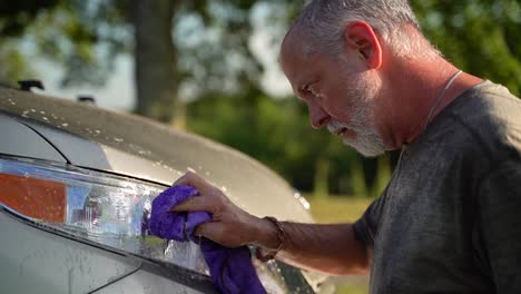 Profile-closeup-of-funny-man-washing-car-headlights-and-spraying-water-in-his-face-by-accident