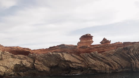 Panorámica-A-Cámara-Lenta-A-La-Derecha-De-Las-Formaciones-Rocosas-Frente-A-La-Costa-De-Ibiza-Al-Amanecer,-España