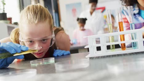 maestra diversa y escolares felices teniendo clase de ciencias en el laboratorio escolar