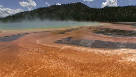 steam rises from a geothermal lake at the grand prismatic springs in florida