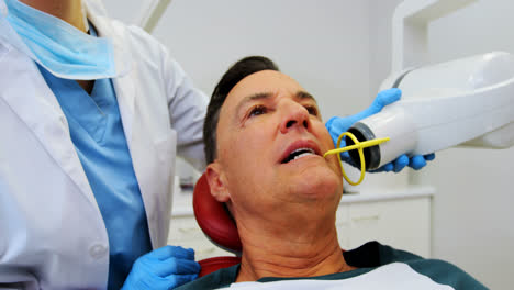 Dentist-examining-a-male-patient-with-tool