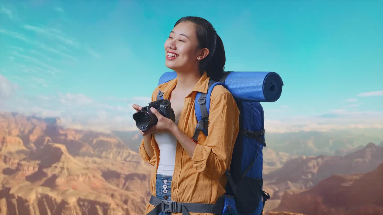 Side View Of Asian Female Hiker With Mountaineering Backpack Smiling And Holding A Camera In Her Hands Then Looking Around While Traveling At The Top Of Mountain