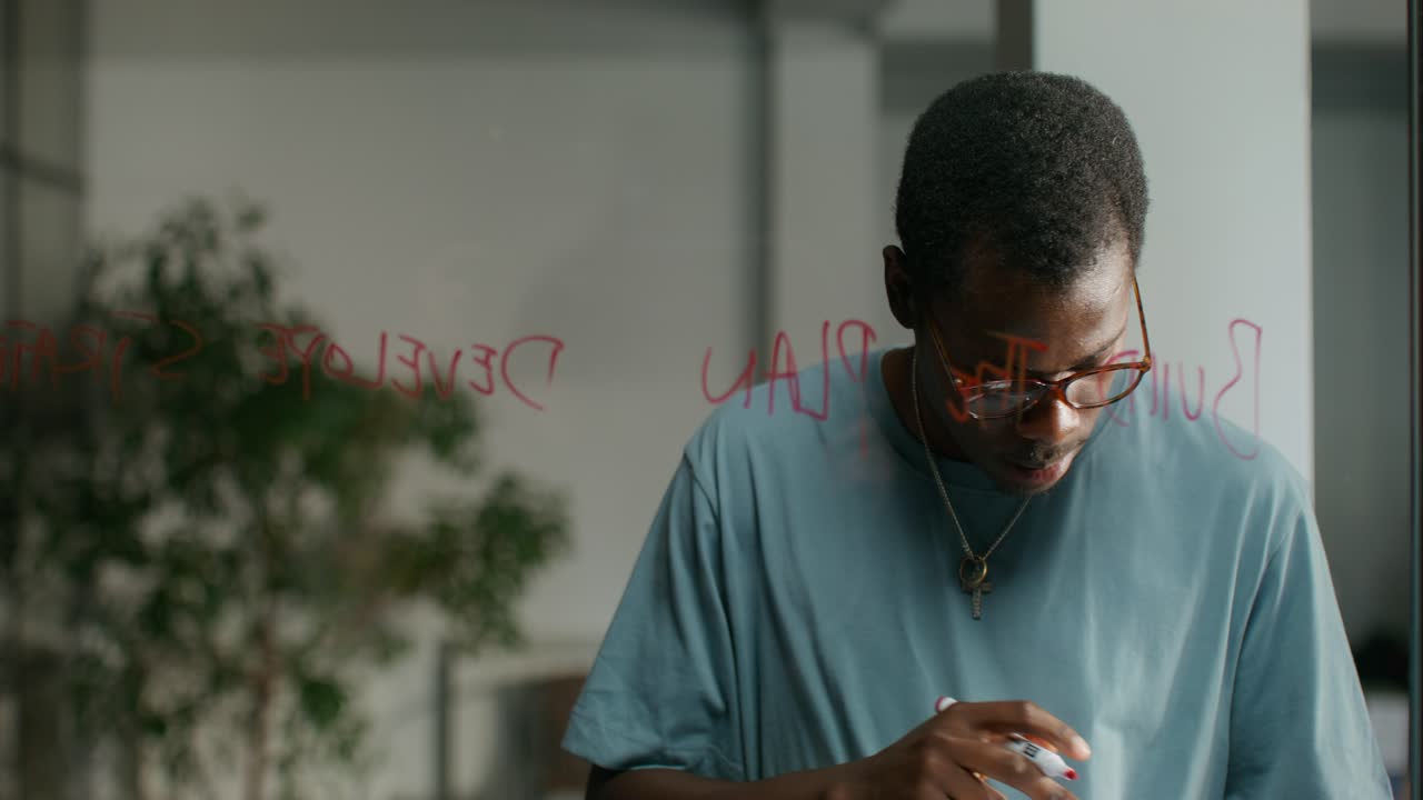 Man Writing Ideas on Glass