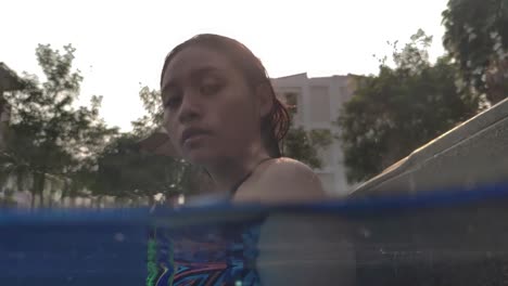 Split-underwater-shot-of-Southeast-Asian-girl-looking-at-the-camera