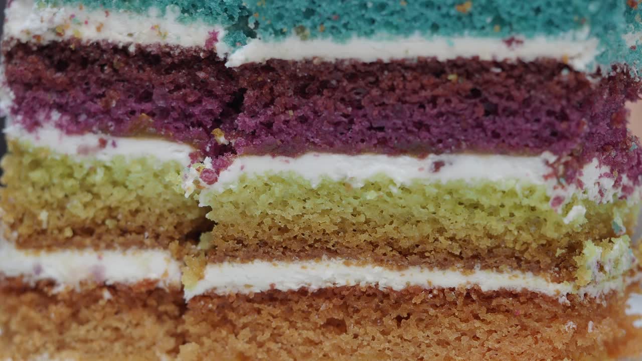 Primo piano di una torta a strati colorata che viene affettata