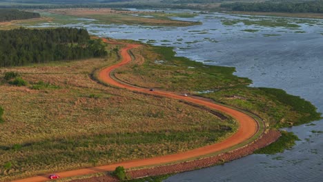 Automóviles-Avanzando-Por-Un-Camino-De-Tierra-A-Lo-Largo-De-Un-Río-En-Misiones,-Argentina