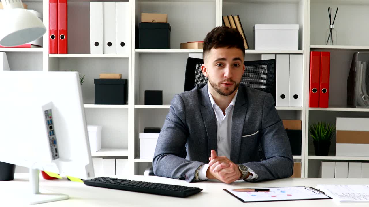 молодой бизнесмен смотрит на камеру в современном офисе